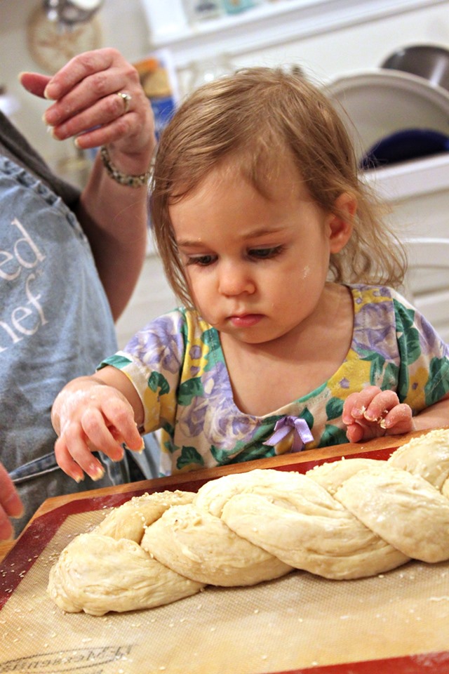 Toddler sprinkling seeds on her challah dough